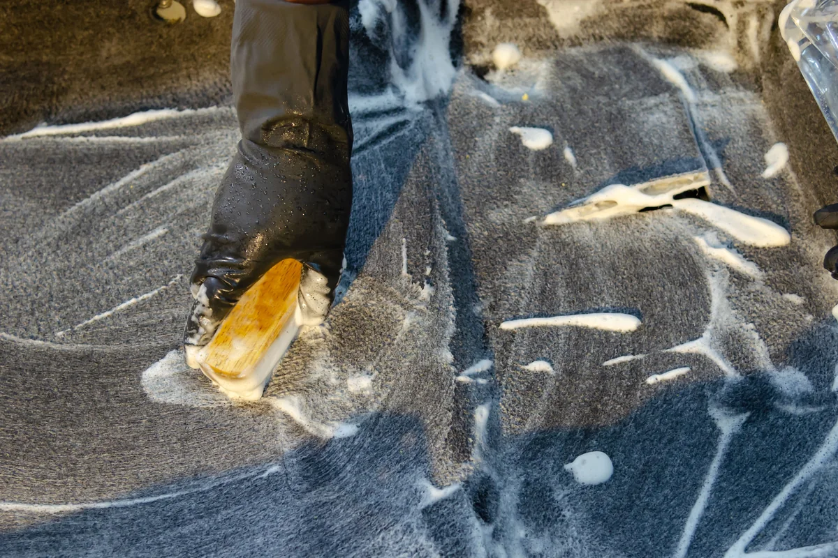 Carpet being scrubbed with a brush and cleaning solution
